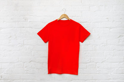 Red t-shirt on a hanger against a white brick wall test.